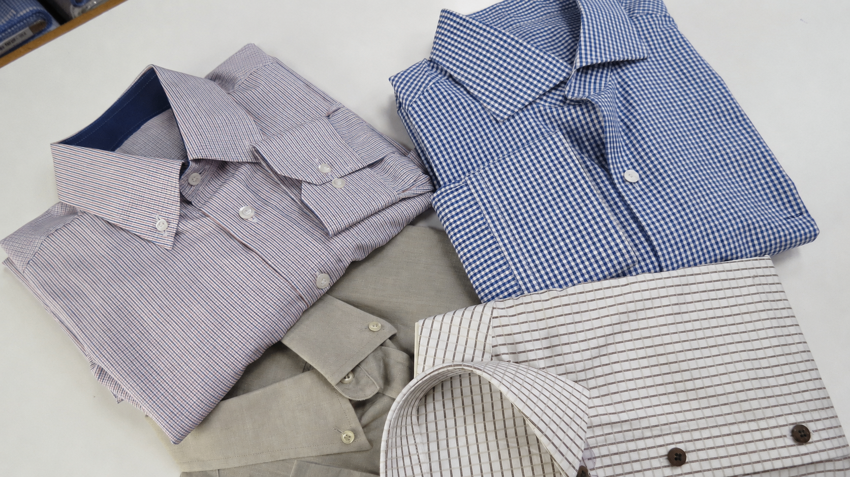 Detalhe de punho de camisa em tecido xadrez fino com botões em madrepérola